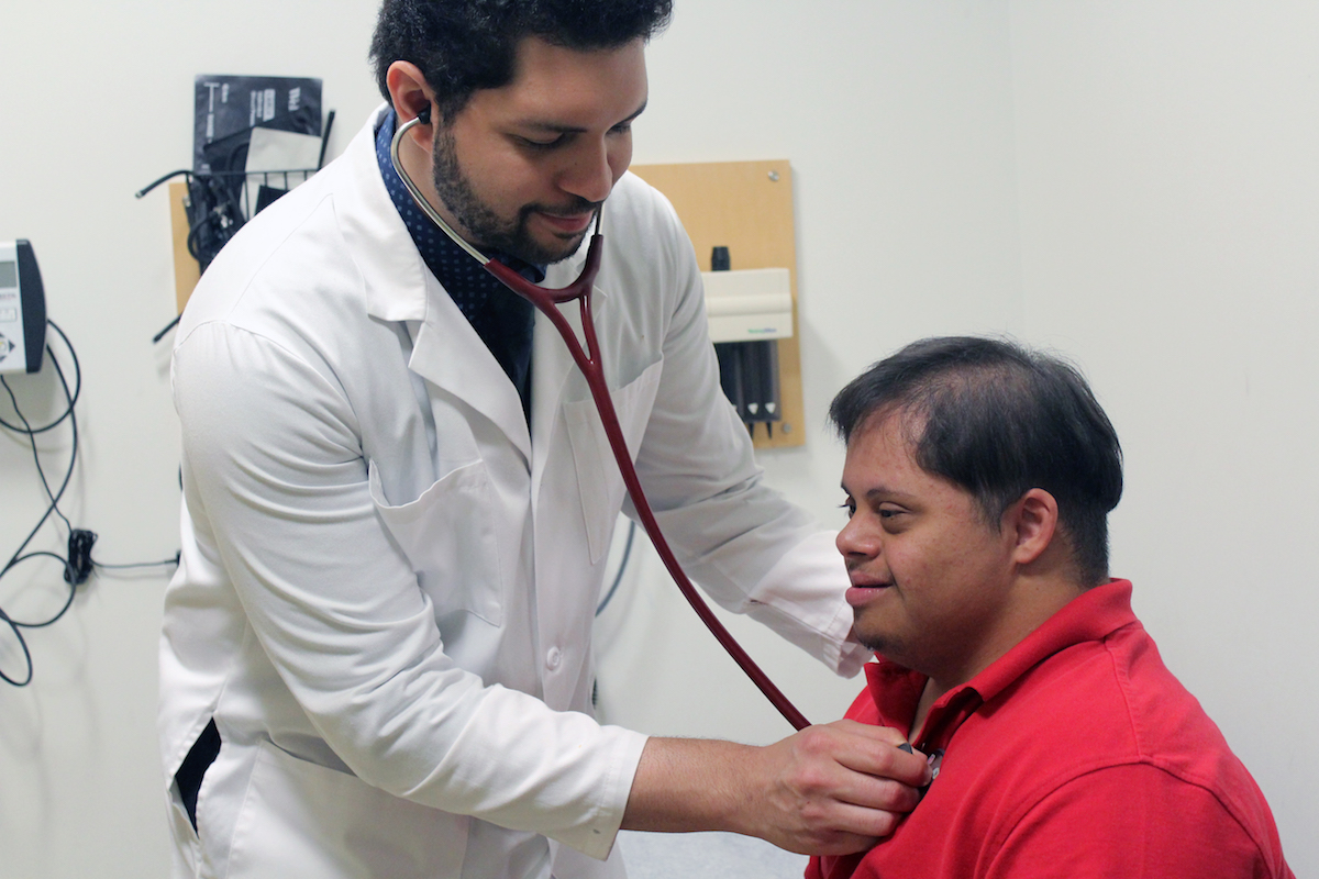 Photo of patient with Down syndrome and doctor using stethoscope on him