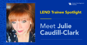 LEND Trainee Spotlight: Julie Caudill-Clark. She has long, ginger hair tied back and bright, green eyes. She is wearing a navy floral top and headphones, smiling for the photograph.