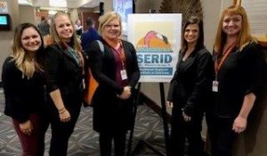 ASL Team standing in front of SERID Conference poster