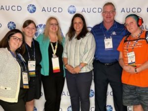 six HDI staff and students standing in front of the AUCD conference banner