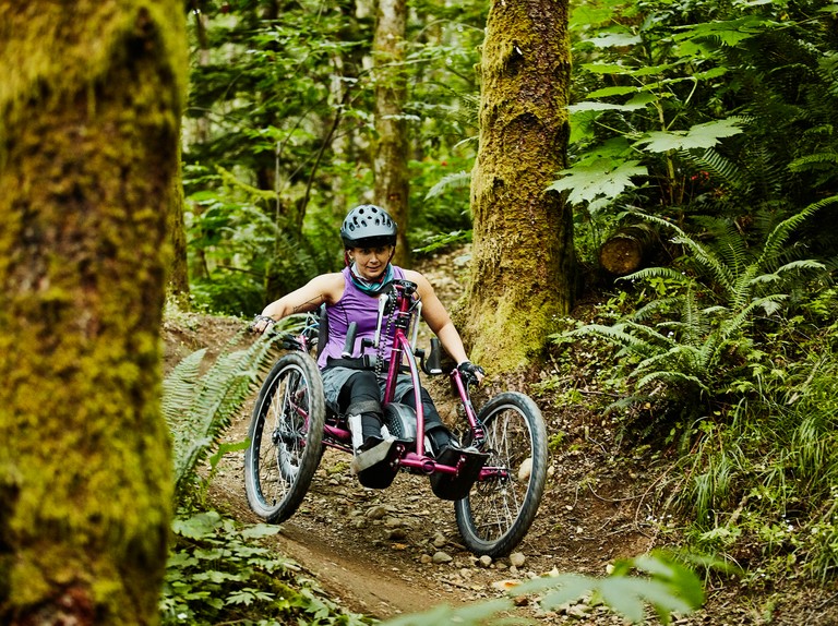 Person riding an adaptive bike on a forest trail