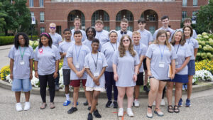 Group photo of campers standing in front of the library on campus